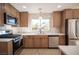 Beautiful kitchen featuring stainless steel appliances, wood cabinets and a large window with a view of the backyard at 9817 Kernville Dr, Las Vegas, NV 89134