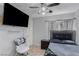 Well-lit bedroom with tiled floor, ceiling fan, wall-mounted television and comfortable chair at 1066 Aspen Valley Ave, Las Vegas, NV 89123