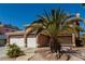 Charming home with a three-car garage and well-maintained landscaping and desert landscaping with a palm tree in the yard at 1066 Aspen Valley Ave, Las Vegas, NV 89123