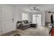 Welcoming living room with a gray sectional, carpeted floors, and a sliding glass door leading to the backyard at 12107 Frost Lime Rd # 1, Las Vegas, NV 89183