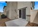 Rear patio featuring tan stucco siding, neutral privacy fence, rock cover, and sliding glass door at 12107 Frost Lime Rd # 1, Las Vegas, NV 89183
