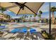 Community swimming pool featuring lounge chairs, umbrellas, palm trees, and gated entrance at 12107 Frost Lime Rd # 1, Las Vegas, NV 89183