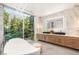 A luxury bathroom shows a freestanding tub and double vanity with a view of the garden at 13 Rockstream Dr, Henderson, NV 89012