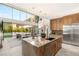 Bright kitchen with a marble island, stainless steel appliances, wooden cabinets, and an open view to the living area at 13 Rockstream Dr, Henderson, NV 89012