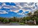 Inviting community entrance with manicured landscaping, mature trees, and clear signage under a partly cloudy sky at 1353 Volturno Way, Henderson, NV 89052