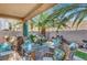 Covered patio featuring wicker seating, floral decor, and outdoor dining under palm trees at 1353 Volturno Way, Henderson, NV 89052