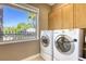 Bright laundry room with a washer and dryer, with a palm tree view from the window at 2008 Winter Wind St, Las Vegas, NV 89134