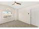 Bright bedroom features a ceiling fan, neutral carpet, and a large window with neighborhood views at 215 Sunlight Peak St, Henderson, NV 89012