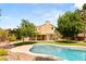 Backyard featuring a large pool, lush landscaping, mature trees, and a covered patio for relaxation at 215 Sunlight Peak St, Henderson, NV 89012