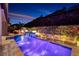 Beautiful backyard pool with illuminated water feature and manicured hillside in background at 33 Desert Juniper Ln, Henderson, NV 89011