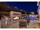 An outdoor seating area has an outdoor kitchen with a grill, fireplace and a view of the pool at 33 Desert Juniper Ln, Henderson, NV 89011