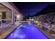 Night view of a private pool with water features and beautifully landscaped backyard with fire pit at 33 Desert Juniper Ln, Henderson, NV 89011