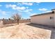 A spacious backyard with a tree, surrounded by a fence under a blue sky with white clouds at 3409 Judson Ave, North Las Vegas, NV 89030