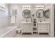 Bright bathroom features dual vanity sinks, round mirrors, and a tub with decorative tile surround at 3409 Judson Ave, North Las Vegas, NV 89030