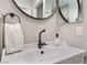 Close-up of a vanity sink with a black faucet, white towel, and round dark-framed mirror at 3409 Judson Ave, North Las Vegas, NV 89030