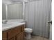A bathroom with a wood vanity and a shower-tub combo with a striped curtain at 3512 Trilogy Dr, Las Vegas, NV 89108