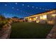 Expansive backyard with lush green grass, outdoor seating area, string lights, creating a tranquil outdoor oasis at 6325 Gambetta St, Las Vegas, NV 89115