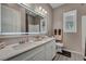 Modern bathroom boasts a double sink vanity with a large, illuminated mirror and stylish wood-look tile flooring at 6325 Gambetta St, Las Vegas, NV 89115