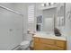 Clean bathroom with a white shower, toilet, and vanity with a large mirror and ample lighting at 7013 Bisoni St, Las Vegas, NV 89149