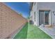 Narrow backyard with artificial grass and rock landscaping alongside a home with glass sliding door at 764 Aurora Vale Pl, Henderson, NV 89011
