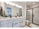 Modern bathroom featuring dual sinks, quartz countertops, a large mirror, and a frameless glass shower at 764 Aurora Vale Pl, Henderson, NV 89011