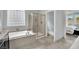 Bright bathroom featuring a soaking tub, glass shower, and view into the main bedroom at 8134 Maddingley Ave, Las Vegas, NV 89117