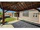 An inviting covered backyard patio features a concrete floor, a hot tub, and lush green landscaping at 9638 Smiley Creek St, Las Vegas, NV 89178