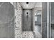 Modern shower featuring gray stone tiles and a black and white tiled accent wall at 9638 Smiley Creek St, Las Vegas, NV 89178
