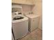 A laundry room with modern side-by-side washer and dryer units and neutral tile flooring at 1050 Spotted Saddle St, Henderson, NV 89015
