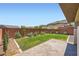 A quaint backyard featuring grass, desert landscaping, and a small brick patio at 10693 Harvest Green Way, Las Vegas, NV 89135