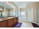 Bathroom featuring double sinks, vanity with marble countertops, separate tub and shower at 10693 Harvest Green Way, Las Vegas, NV 89135