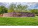 Stone sign, 'The Mesa', amidst lush greenery and trees, marking a welcoming community entrance at 10693 Harvest Green Way, Las Vegas, NV 89135