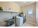 Functional laundry room with tiled floors, washer, dryer, shelving, and natural light at 10693 Harvest Green Way, Las Vegas, NV 89135
