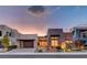 Stunning modern home featuring stone accents, lush landscaping, and a multi-car garage at dusk at 2180 Skyline Heights Ln, Henderson, NV 89052