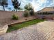 A spacious backyard with brick pavers, a small patch of grass, and tasteful landscaping along the retaining wall at 2947 Caxton Grove Dr, Henderson, NV 89052