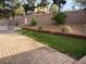 A spacious backyard with brick pavers, a small patch of grass, and tasteful landscaping along the retaining wall at 2947 Caxton Grove Dr, Henderson, NV 89052