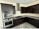 Modern kitchen features stainless steel appliances, dark wood cabinets, granite countertops and tile flooring at 2947 Caxton Grove Dr, Henderson, NV 89052