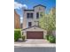 Charming stucco home featuring a two-car garage, manicured bushes, and well-maintained landscaping at 345 Gracious Way, Henderson, NV 89011