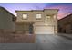 Two-story home showcasing a beige stucco facade, a two-car garage, and low-maintenance landscaping at 3532 Carisbrook Dr, North Las Vegas, NV 89081