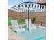 Inviting in-pool lounge chairs under a striped umbrella offers a relaxing resort-like experience at 38 Costa Tropical Dr, Henderson, NV 89011