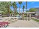 Community pool area featuring a fire pit, bar with seating, and beautiful landscaping with tall palm trees at 5055 W Hacienda Ave # 1136, Las Vegas, NV 89118