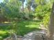 Lush backyard featuring green grass, mature trees, and a stone pathway at 5305 Bright Sun Ct, Las Vegas, NV 89130