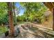 Landscaped backyard featuring a stone patio, stone benches, and mature shade trees at 5305 Bright Sun Ct, Las Vegas, NV 89130