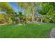 Spacious backyard featuring a lush lawn, trees, and multiple patio areas, ideal for outdoor living at 5305 Bright Sun Ct, Las Vegas, NV 89130