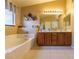Bright bathroom with a dual vanity, bathtub, and decorative wall accents; featuring tile floors, a window, and neutral walls at 6279 Dollar Bill Ct, Las Vegas, NV 89141