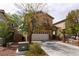 Front exterior view of home with a two-car garage and mature landscaping at 6279 Dollar Bill Ct, Las Vegas, NV 89141