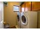 Functional laundry room with washer, dryer, and wooden cabinets at 6279 Dollar Bill Ct, Las Vegas, NV 89141