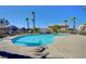 Community pool surrounded by palm trees, houses, and a metal fence on a clear day at 6433 Buck Jones Ave # 102, Las Vegas, NV 89122