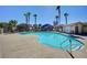 Community pool with trees, a nearby pool house, and several tall palm trees under a clear sky at 6433 Buck Jones Ave # 102, Las Vegas, NV 89122