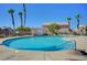 Community pool surrounded by palm trees and a concrete deck, enclosed by a metal fence at 6433 Buck Jones Ave # 102, Las Vegas, NV 89122